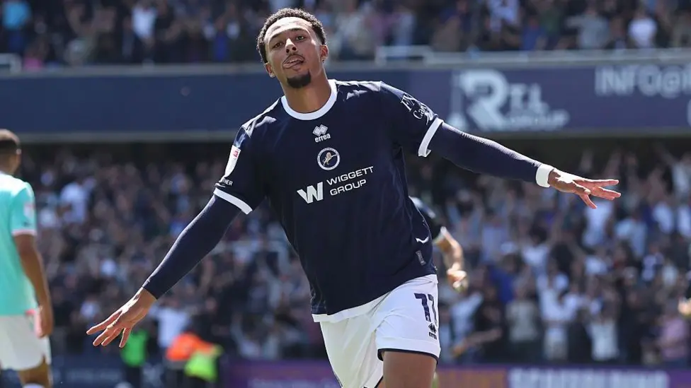 A footballer in a navy shirt celebrates on the pitch
