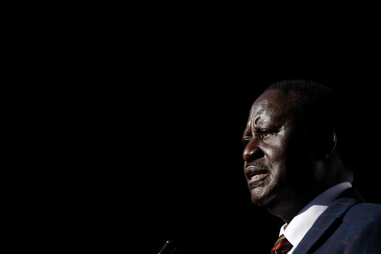 A man speaking at a microphone against a dark background