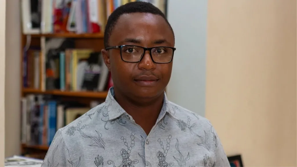 A man wearing glasses in front of bookshelves
